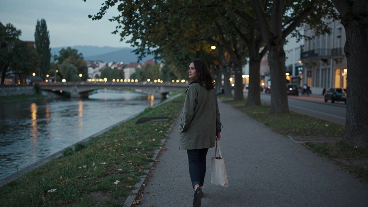 A woman walking peacefully along the Isère River at dusk in Grenoble.